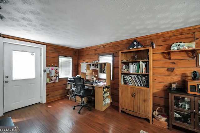 office area with a textured ceiling, wood walls, and dark hardwood / wood-style flooring