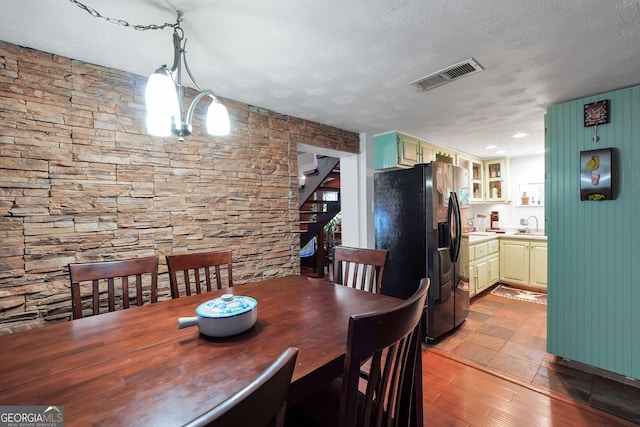 dining room with a textured ceiling, light hardwood / wood-style flooring, an inviting chandelier, and sink