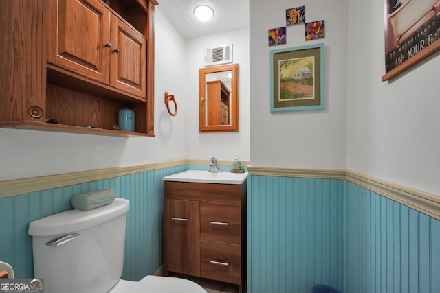 bathroom with toilet, a textured ceiling, and vanity