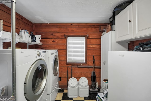 laundry area with washer and dryer, cabinets, wood walls, and a textured ceiling