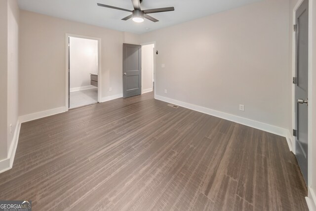 unfurnished bedroom with dark wood-type flooring, connected bathroom, and ceiling fan