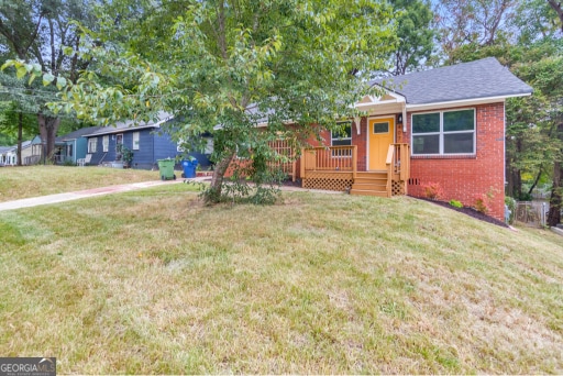 single story home with a wooden deck and a front lawn