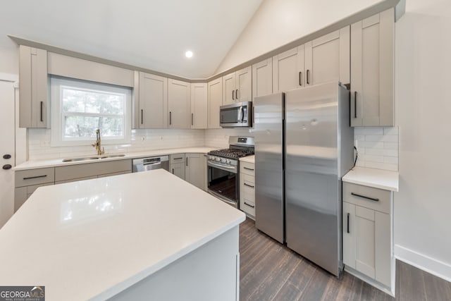 kitchen featuring backsplash, stainless steel appliances, sink, lofted ceiling, and dark hardwood / wood-style floors