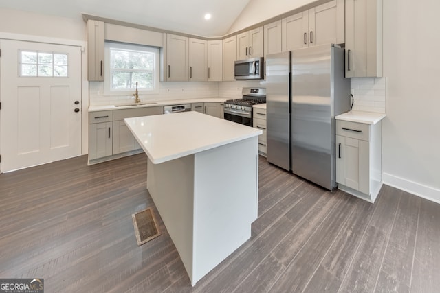 kitchen with stainless steel appliances, dark hardwood / wood-style flooring, a center island, sink, and vaulted ceiling