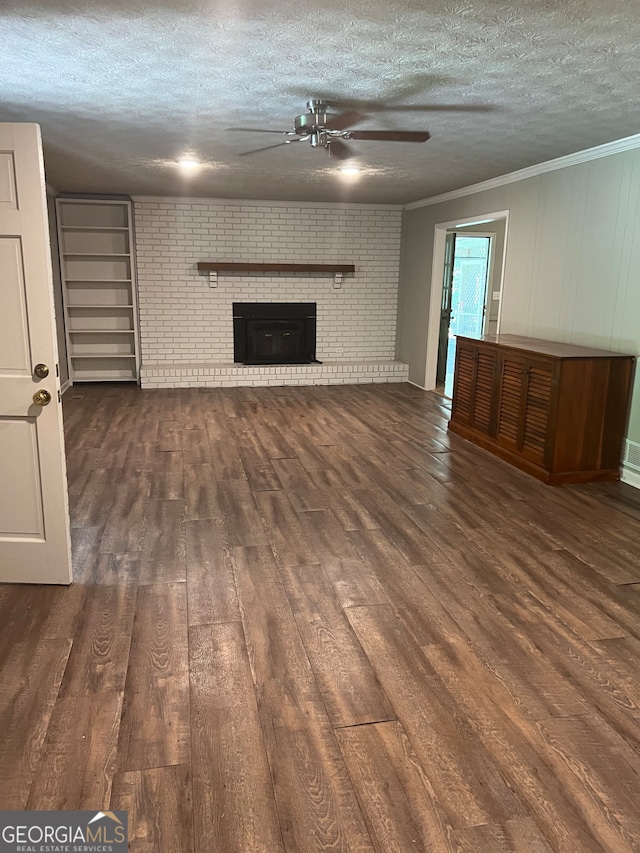 unfurnished living room featuring a textured ceiling, dark hardwood / wood-style floors, a fireplace, crown molding, and ceiling fan