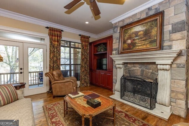 living room featuring a fireplace, wood-type flooring, french doors, crown molding, and ceiling fan