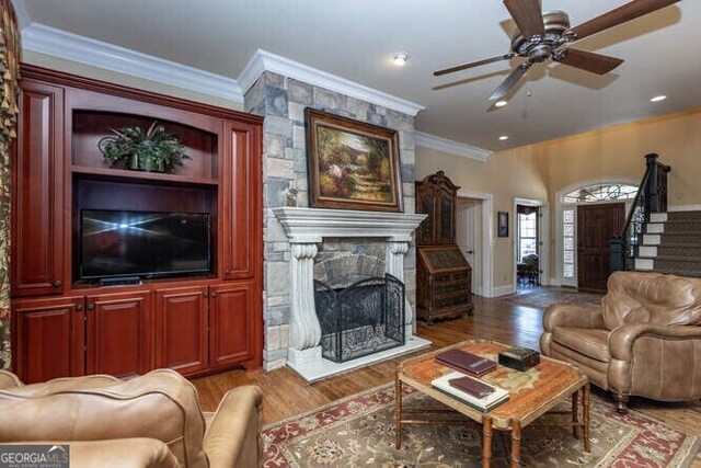 living room featuring ceiling fan, wood-type flooring, and ornamental molding