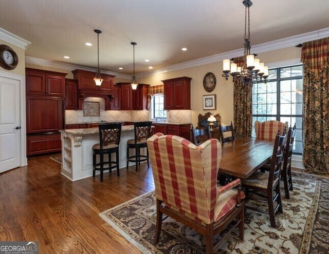 dining space with ornamental molding, dark wood-type flooring, and a notable chandelier