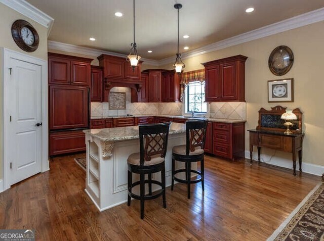 kitchen with a kitchen island, a breakfast bar area, decorative light fixtures, dark wood-type flooring, and decorative backsplash