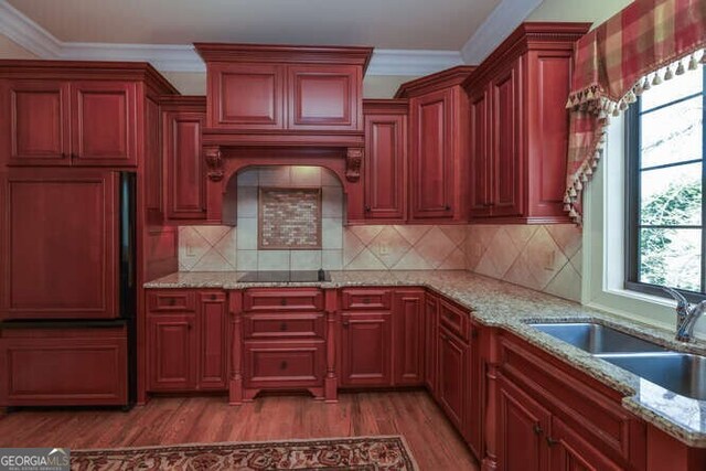 kitchen with crown molding, light stone counters, sink, black electric cooktop, and dark wood-type flooring