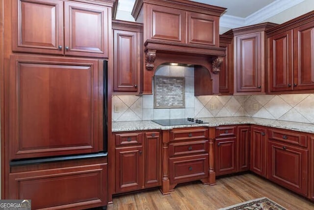 kitchen with custom range hood, light wood-type flooring, black electric stovetop, tasteful backsplash, and ornamental molding