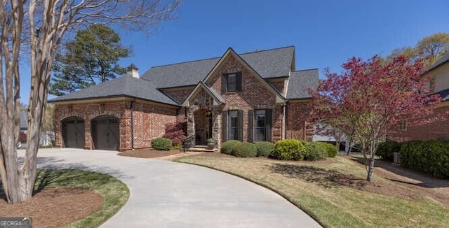 tudor house featuring brick siding, an attached garage, and driveway