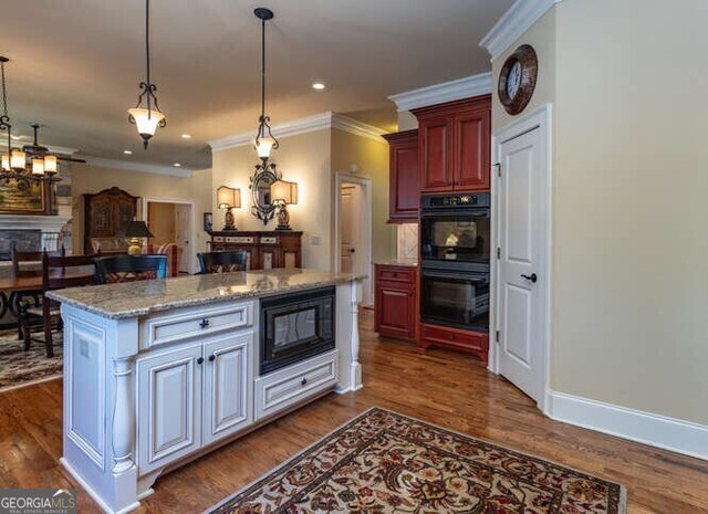 kitchen with dark hardwood / wood-style floors, black appliances, hanging light fixtures, light stone counters, and white cabinets