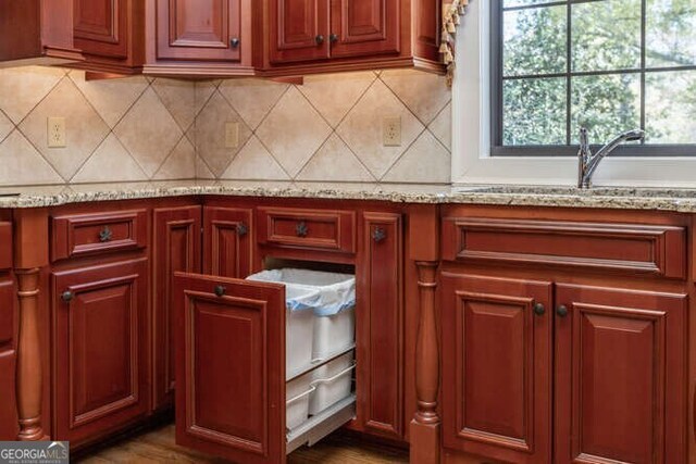 kitchen featuring a wealth of natural light, light stone counters, sink, and decorative backsplash