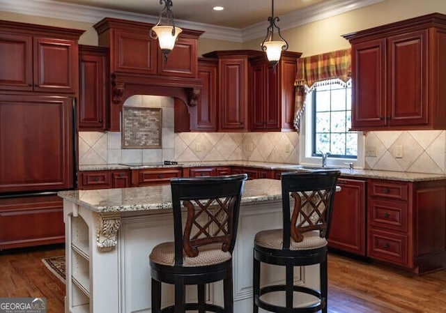 kitchen featuring dark brown cabinets, a center island, dark wood-type flooring, light stone counters, and hanging light fixtures