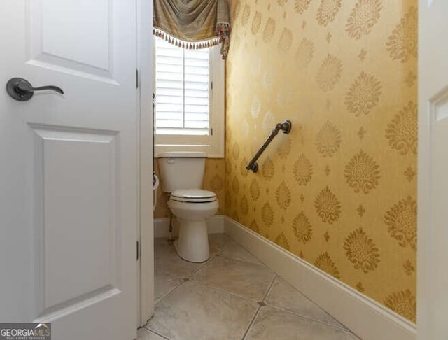 bathroom featuring wallpapered walls, toilet, baseboards, and tile patterned flooring