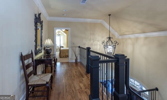 corridor featuring crown molding, dark wood-type flooring, lofted ceiling, and an inviting chandelier