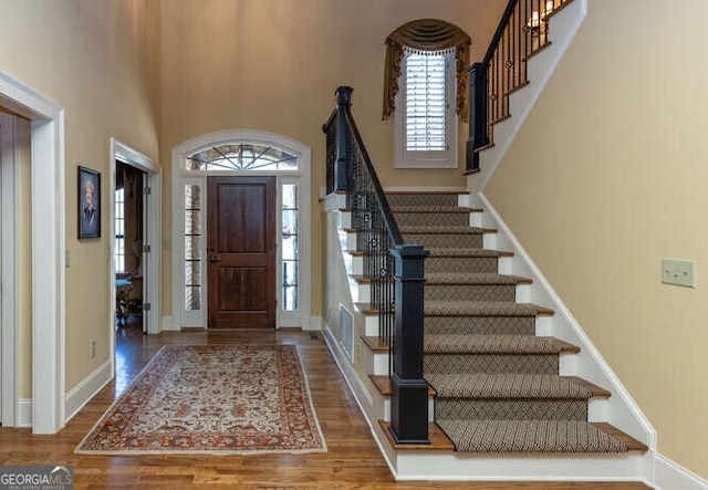 entrance foyer featuring hardwood / wood-style flooring and a towering ceiling