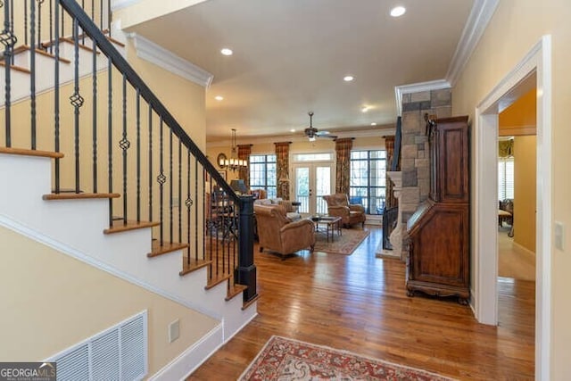 stairway with recessed lighting, visible vents, wood finished floors, and ornamental molding