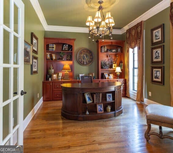 office area with wood-type flooring, a notable chandelier, and ornamental molding