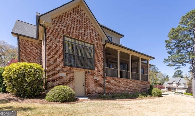 view of side of property with brick siding and a sunroom