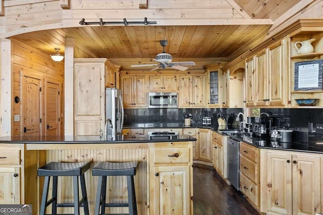 kitchen with ceiling fan, light brown cabinets, stainless steel appliances, and a breakfast bar area