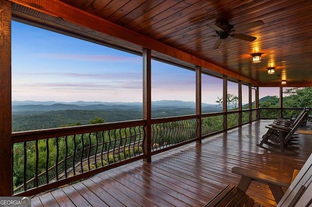 deck at dusk featuring a mountain view and ceiling fan