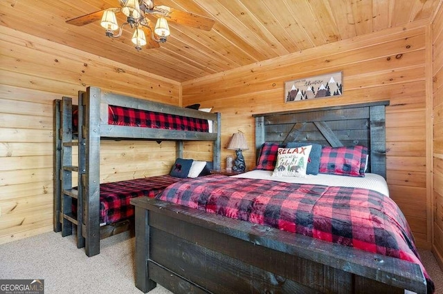 carpeted bedroom with wooden ceiling, wood walls, and ceiling fan