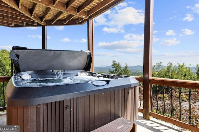 deck with a mountain view and a hot tub