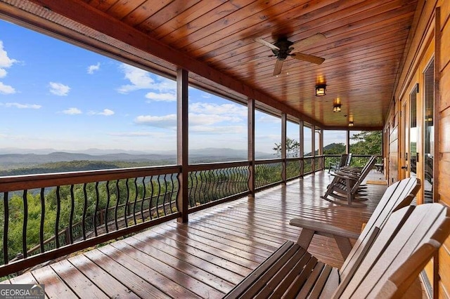 wooden deck featuring a mountain view and ceiling fan