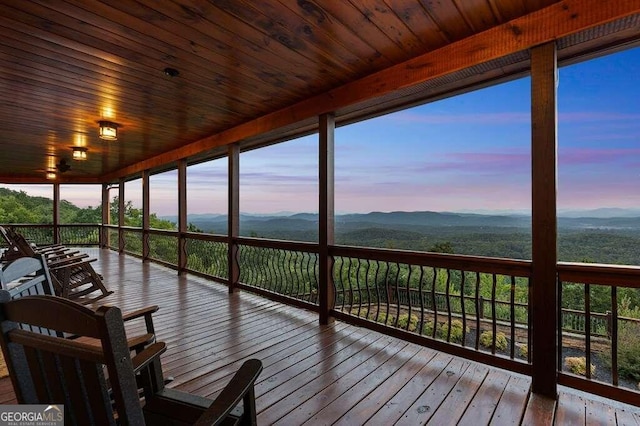 unfurnished sunroom featuring a mountain view, plenty of natural light, and wooden ceiling