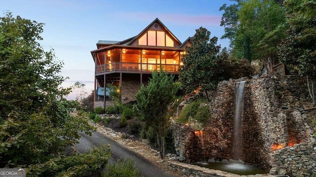 back house at dusk featuring a balcony