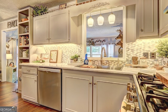 kitchen with a textured ceiling, backsplash, stainless steel appliances, wood-type flooring, and sink