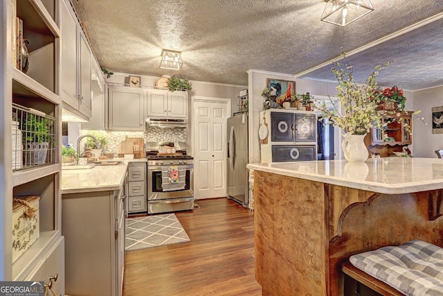 kitchen with crown molding, hardwood / wood-style floors, stainless steel appliances, sink, and a kitchen breakfast bar