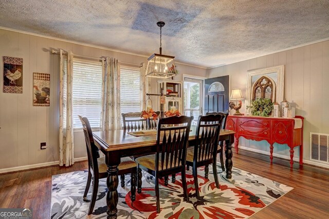 dining area featuring a textured ceiling, hardwood / wood-style flooring, and a chandelier