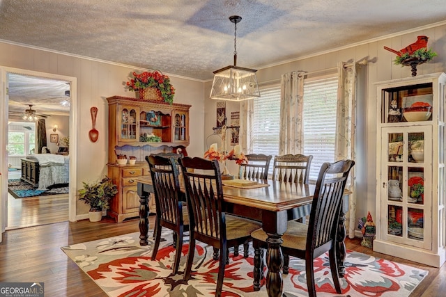 dining room featuring a textured ceiling, ornamental molding, hardwood / wood-style floors, and ceiling fan with notable chandelier