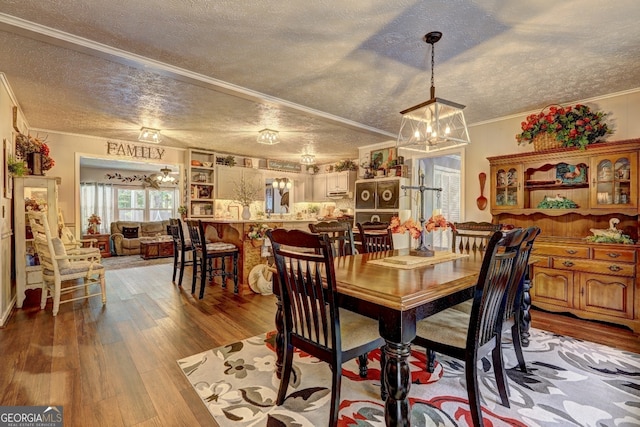 dining area with an inviting chandelier, light hardwood / wood-style floors, crown molding, and a textured ceiling