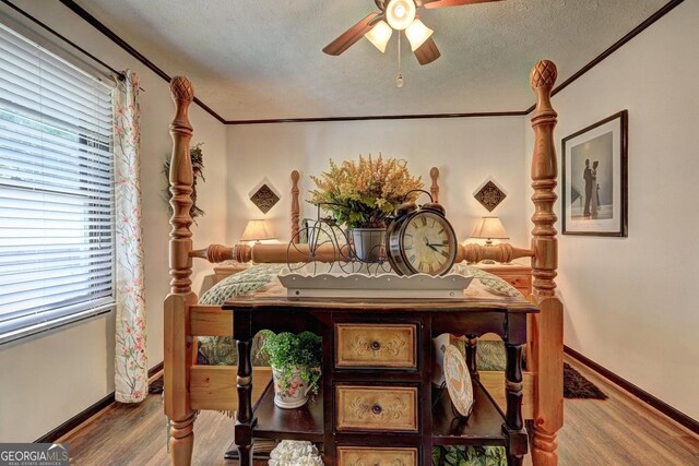 bedroom featuring a textured ceiling, hardwood / wood-style flooring, ceiling fan, and multiple windows