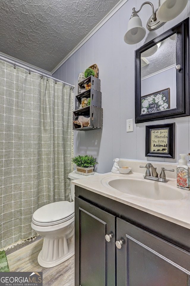 bathroom with hardwood / wood-style flooring, crown molding, toilet, vanity, and a textured ceiling