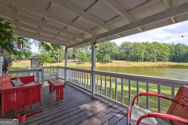 deck with a water view and a lawn