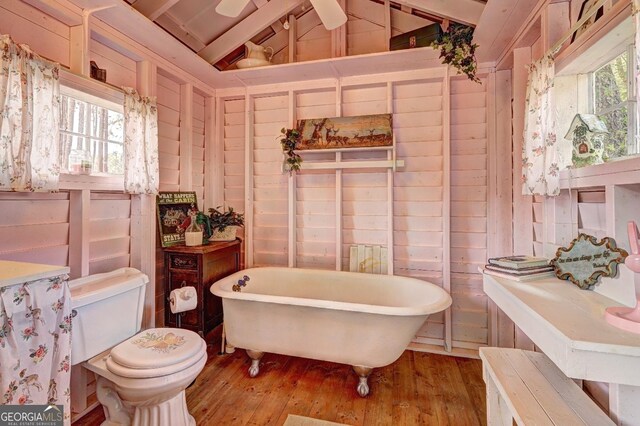 bathroom with toilet, a bathing tub, lofted ceiling with beams, and a healthy amount of sunlight