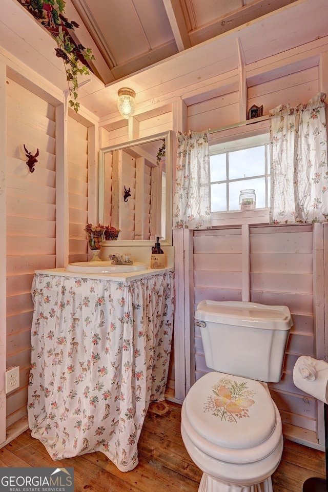 bathroom with toilet, hardwood / wood-style flooring, and wooden walls