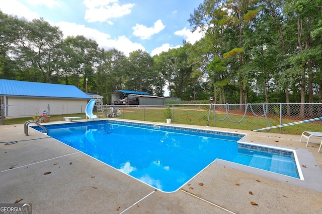 view of pool with a lawn, a water slide, and a patio