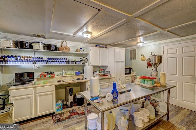 kitchen with a textured ceiling, white cabinetry, and light hardwood / wood-style floors