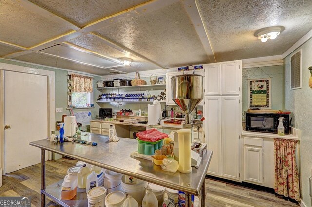 kitchen with white cabinetry, a textured ceiling, and light hardwood / wood-style floors