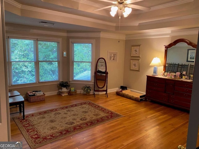 living area with a tray ceiling, ceiling fan, and light hardwood / wood-style flooring