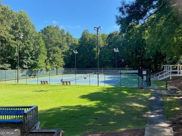 view of tennis court featuring a lawn