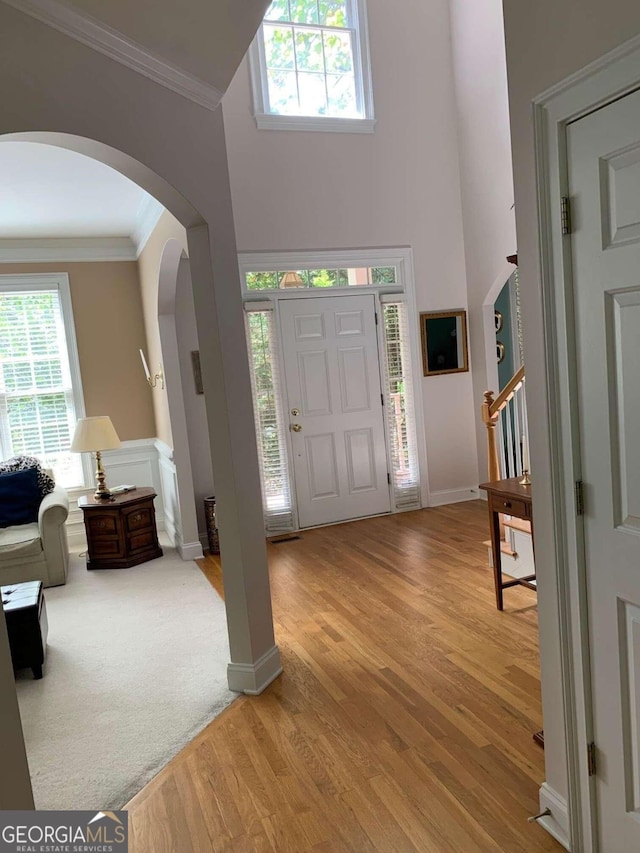 foyer entrance featuring plenty of natural light, ornamental molding, and light hardwood / wood-style floors