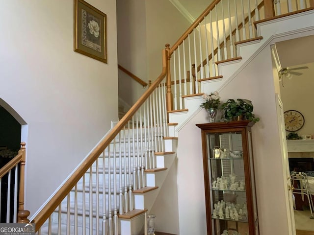 2631 Gladstone Ter, Woodstock, GA 30189 - stairway with a fireplace, ceiling fan, ornamental molding, and a high ceiling