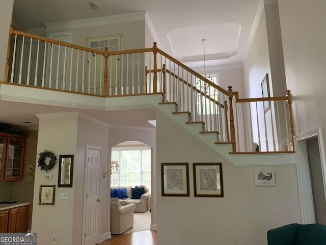 2631 Gladstone Ter, Woodstock, GA 30189 - stairs with an inviting chandelier, a high ceiling, crown molding, baseboards, and arched walkways